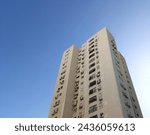 Architectural elements of an older residential tower block against blue sky. Tall residential building in Israel 