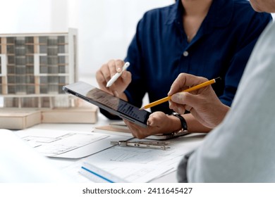 Architectural or engineers are explaining construction plans using tablets and brainstorming ideas for a successful construction project.