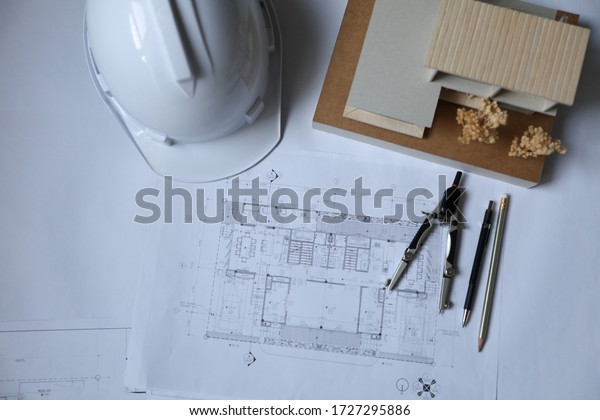 Architectural\
plan, laptop, dividers ,pencil ,pen ,ruler, glasses and smartphone\
and blueprint on wooden table. Top\
view