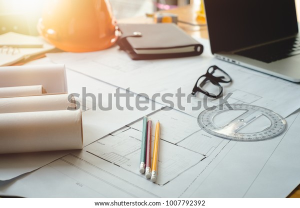 Architectural plans work apace. Architectural\
project,blueprints,pencil ,labtop and divider compass on wooden\
desk table.Construction background.Engineering tools. Copy\
space.Architectural\
Concept