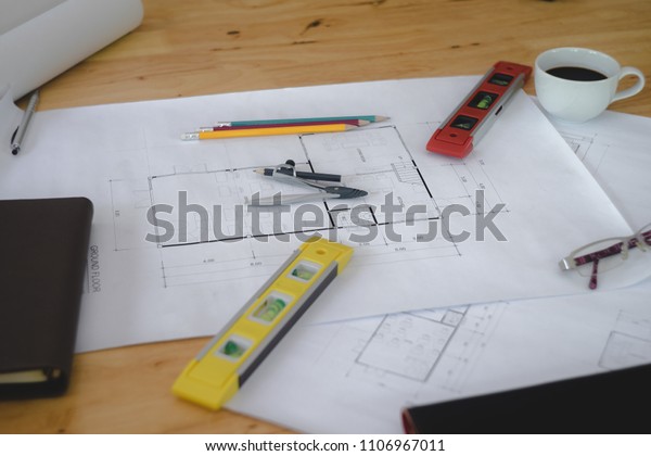 Architectural plans work space top view.\
Architectural project, blueprints,pencil and divider compass on\
wooden desk table.Construction background.Engineering tools. Copy\
space.Architectural\
Concept