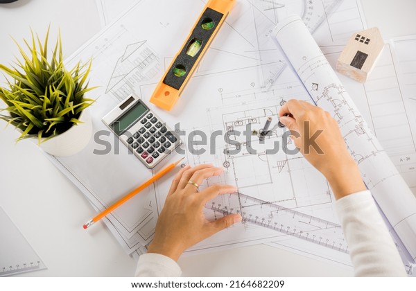 Architectural project workplace. Engineer
sketching construction project, Architect drawing with divider
compass on house plan blueprint paper for repair tools on table
desk at architecture
office