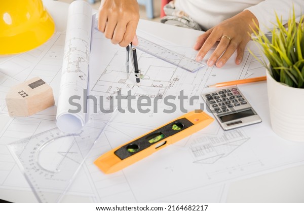 Architectural project workplace. Engineer\
sketching construction project, Architect drawing with divider\
compass on house plan blueprint paper for repair tools on table\
desk at architecture\
office