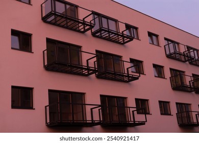 An architectural structure featuring numerous windows and multiple balconies that enhance its design and livability for the residents