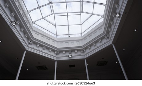 Architectural view of an octagonal glass ceiling skylight with geometric framing, allowing natural daylight into the interior. Modern classic dome design in a public or commercial building.