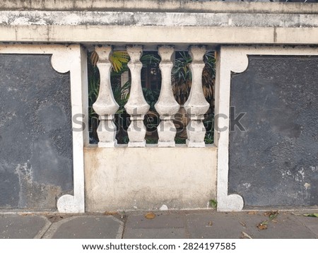 Architectural wall with balusters and weathered texture, creating a patterned divide.