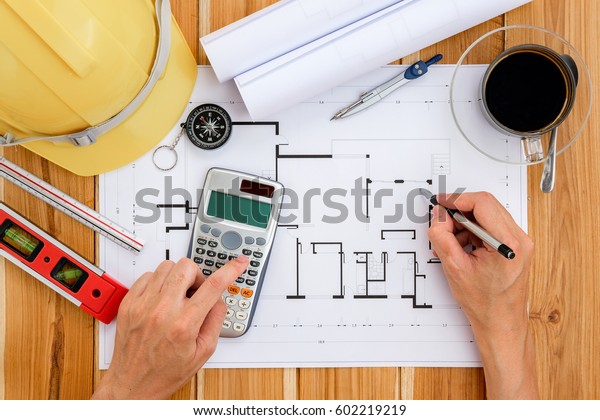 architecture, building,\
business, construction and people concept - close up of architect\
hands working with calculator and pen on house blue\
print.Architecture\
concept.