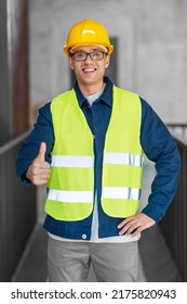 Architektur, Baugewerbe und Baukonzept - glücklicher, lächelnder männlicher Architekt im Helm- und Sicherheitswesten zeigt Daumen-Geste im Büro