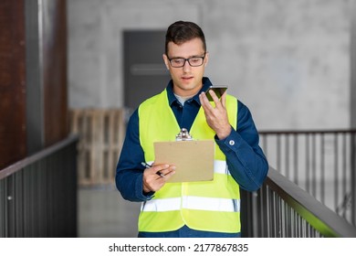 architecture, construction business and building concept - male architect in safety west with clipboard using voice command recorder on smartphone at office - Powered by Shutterstock