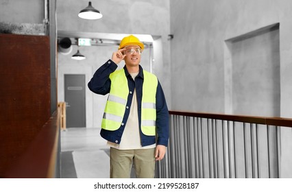 Architecture, Construction Business And Building Concept - Happy Smiling Male Builder In Helmet, Goggles And Safety West At Office