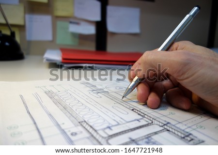 Architecture and construction sketches on the table and the hand of the architect or engineer or designer drawing with a mechanical pencil.