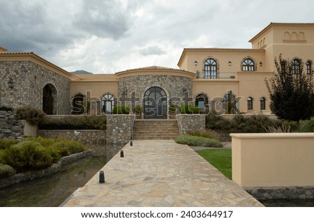 Architecture and design. View of a colonial mansion facade and entrance. A rock path leads the way over the pit filled with water. 