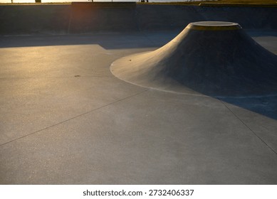 Architecture of an empty skate park featuring a concrete cone obstacle or volcano