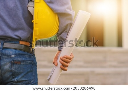 Architecture Engineer holding hard hat on site building construction background