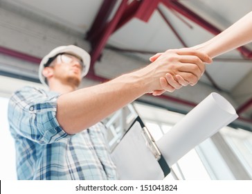 Architecture And Home Renovation Concept - Builder With Blueprint Shaking Partner Hand