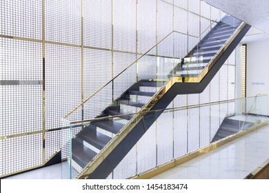 Architecture Of Luxury Wooden Staircase With Glass Railing And Gold Handrail In Golden Grille House Interior.