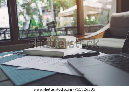 An architecture model with shop drawing paper and laptop on table in office