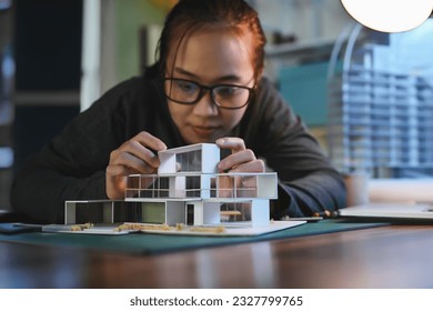 Architecture students diligently make house model building samples with paper architecture and tools at night in their alone room. - Powered by Shutterstock