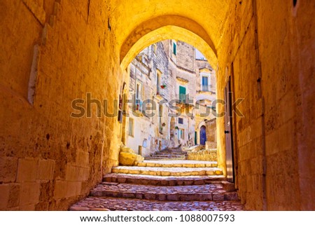 An archway in Matera shot in summer 2017 in the Sassi in south east Italy in Puglia. The stone steps lead up to some residential houses and the camera captures a beautiful golden light on the arch.
