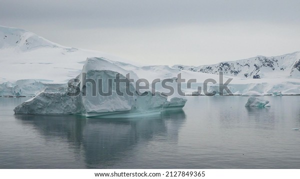Arctic Icebergs. Moving Ice Floes and Ice\
Sheets in the calm Antarctic Sea, Reflection of Antarctica Mountain\
in water surface. Amazing beautiful views of Nature and landscape\
of  Antarctica.