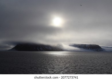 Arctic island covered with fog, sun shining throughout the mist