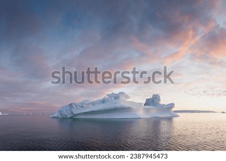 Arctic nature landscape with icebergs in Greenland icefjord with midnight sun. Early morning summer alpenglow during midnight season. Hidden Danger and Global Warming Concept. Tip of the iceberg. 