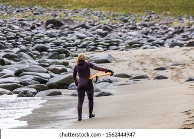 Arctic Surfers Surfing In Norwegian Sea. Unstad, Norwegian Village On Lofoten Islands. Norwegian Sea Coastline. Winter Water Activities Sport.