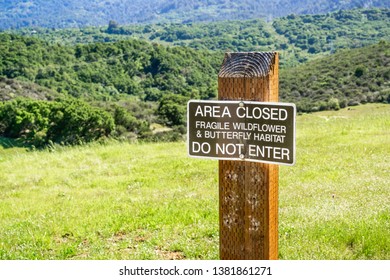 "Area closed Fragile Wildflower & Butterfly Habitat; Do Not Enter" sign posted on the hills of San Francisco bay area in a County Park, California