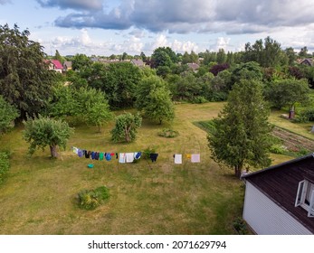 Areal Drone Suburbs View Of Backyard House Garden And Laundry Rope With Laundry. Photo Taken On A Warm Overcast Summer Day.