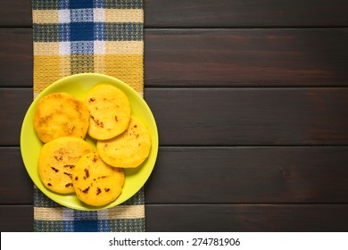 Arepa - Made Of White Or Yellow Corn Meal, Traditionally Eaten For Breakfast Or As Snack In Colombia And Venezuela. Photographed On Dark Wood With Natural Light, Overhead Shot