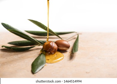Argan oil, used for cosmetics, pouring over two argan seeds on a stone table.