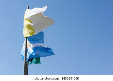 Argentina Flag And Papal Flag Waving Against Blue Sky