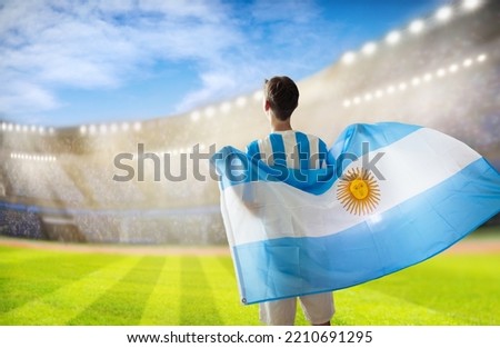 Argentina football supporter on stadium. Argentinian fans on soccer pitch watch team play. Young football player with flag and national jersey cheering for win. Championship game. Vamos Argentina
