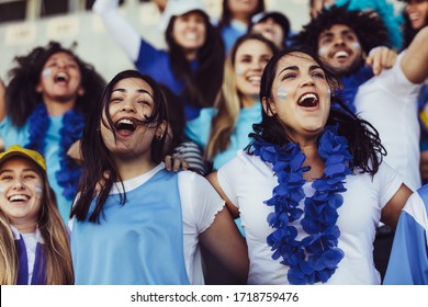 Argentina soccer fans cheering their team with a blue garlands at stadium. Excited football fans at stadium cheering a goal.