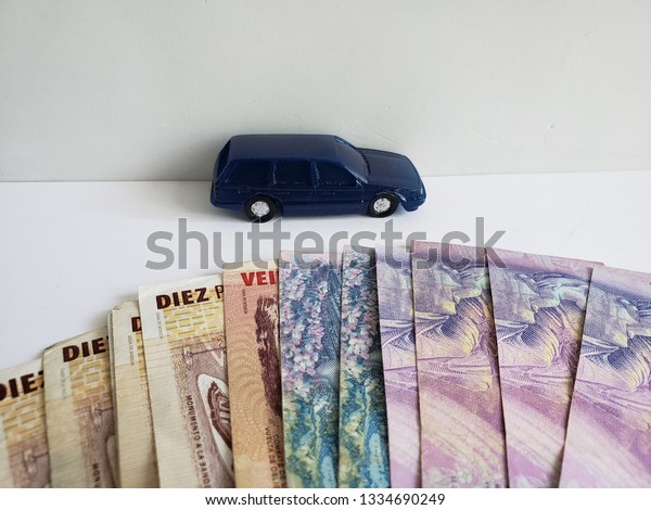 argentine\
banknotes and figure of a car in dark\
blue