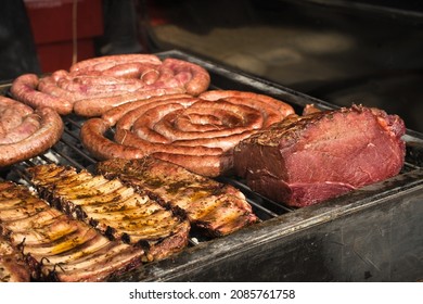 Argentine barbecue, cook preparing grilled meat. Hand holding a brush to oil the meat. Sunny day. Festivity, celebration, banquet. - Shutterstock ID 2085761758