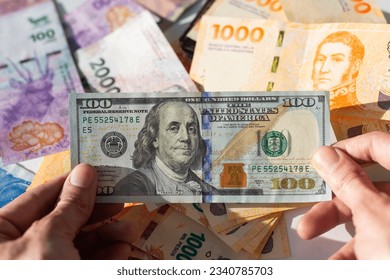 Pesos y dólares argentinos. Billetes en dinero argentino y billetes de cien dólares. Tipo de cambio del peso argentino frente al dólar estadounidense. Concepto de inflación