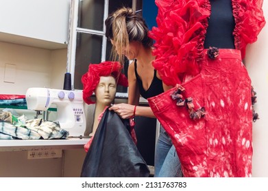 Argentinian Caucasian Young Woman Fashion Designer With A Black Bag In Her Hand Cleaning Her Clothing Design Studio, Organizing Her Workshop After A Day.