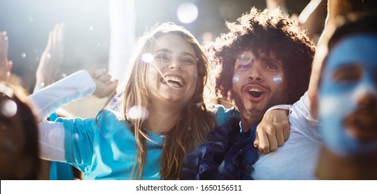 Argentinian couple cheering at a football match. Ecstatic group of people in the stadium during sports event. - Shutterstock ID 1650156511