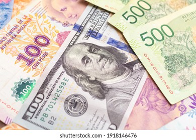 Argentininan Pesos. Money Notes Of The Argetina's Currency And A US Dollar Bill To Represent The Foreign Exchange Theme.