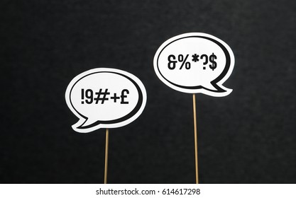 Argument, fight, curse or swearing concept. Disagreement on an online forum or internet. Two speech bubbles argue.. Speech balloon cut from paper of cardboard with wooden stick on a dark background. - Shutterstock ID 614617298