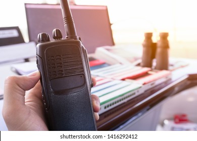 Ari Traffic Controller Using Mobile Radio Pushing Push To Talk (PTT) Button To Transmit Messege To Aerodrome Traffic In Front Of The Desk Which There Are Flight Progress Sttrip And Binoculars On It