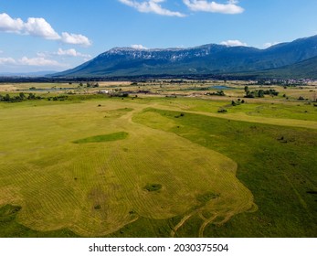 Arial Drone View Of Field At Summer. Field Surrounded By Mountains.