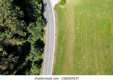 Arial Shot Of An Empty Road Next To A Meadow And A Forest. Idyllic Landscape With Copy Space