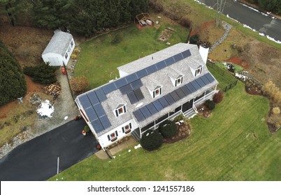 Arial Shot Of White Cape Cod Style House With Solar Panels And Christmas Wreaths 