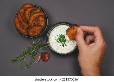 Arial view hand dipping spicy sweet potato chips garnished with chili, rosemary and thyme into yogurt garlic chive dip sauce in black bowls - Powered by Shutterstock