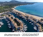 Arial view on blue water of Gulf of Saint-Tropez, boats, houses in Port Grimaud and Port Cogolin, villages on Mediterranean sea with yacht harbour, Provence, summer vacation in France.