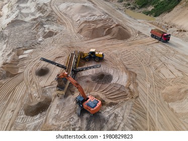 Arial view of the sand open-pit mining with heavy mining machinery. Mobile stone jaw crusher machine in open pit mine. Wheel loader and dump truck in opencast. Exavator on earthworks in quarry.