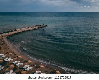 Arial View Of A Small Beach With Umbrellas And A Pier