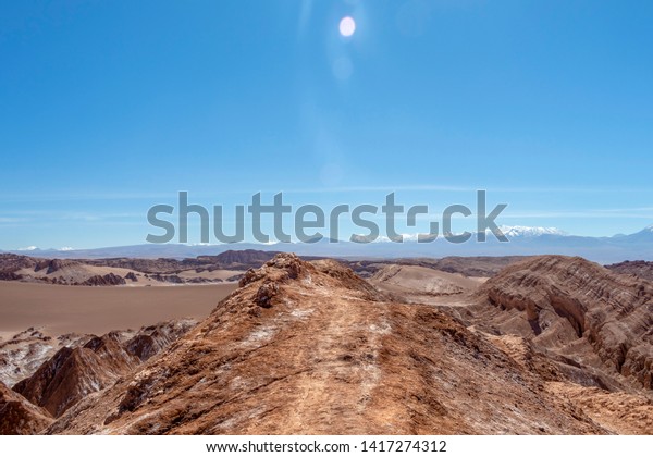 Arid landscape in\
extreme dry desert of Atacama : Moonlike landscape of dunes, rugged\
mountains and distinctive rock formations of Valle de la Luna (Moon\
valley), Northern Chile